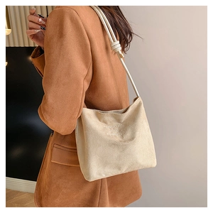Détail du sac fourre-tout en suède crème avec broderie et bandoulière en corde nouée