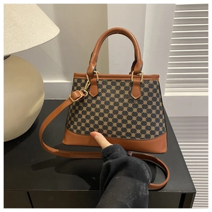 Detail of vintage patterned crossbody bag with brown leather handles and adjustable strap