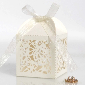 Detail view of laser-cut hollow pattern and ribbon bow on beige wedding favor gift box