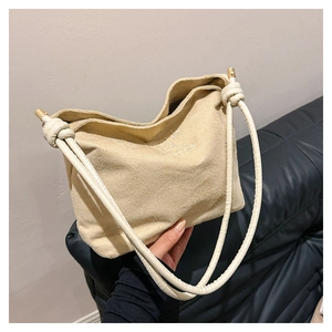 Détail du grand sac cabas en daim beige avec lettrage blanc et détails de nœuds fins