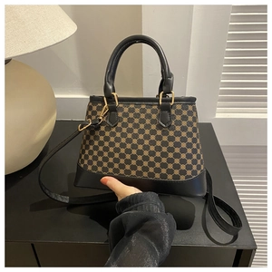 Detail view of vintage checkered handbag with golden pattern and black leather handles