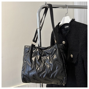 Détail d'un grand sac cabas noir matelassé avec surpiqûres à chevrons sur un cintre