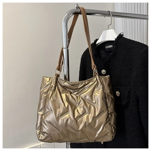 Détail du sac cabas matelassé or champagne avec bandoulières en cuir sur fond en tweed