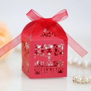 Detail view of a laser-cut red paper candy box featuring reindeer silhouettes and a ribbon