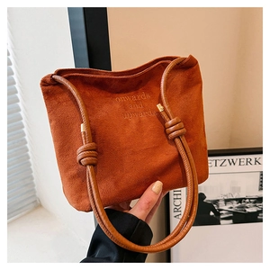 Détail du sac cabas en daim rouge rouille avec bandoulière nouée et texte