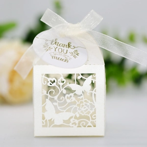 Detailed laser-cut pearl white wedding favor box with butterfly pattern and silk ribbon