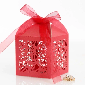 Close-up of red laser-cut gift box with floral patterns and a red organza ribbon bow