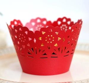 Close-up of red laser-cut cupcake wrappers with hollow sunflower and rose patterns