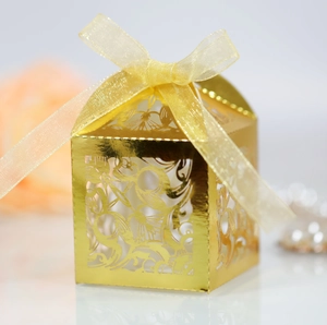 Détail boîte à bonbons dorée découpée au laser avec motifs floraux et ruban élégant