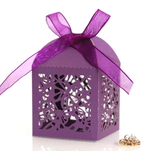 Close-up of purple laser-cut wedding favor box with a satin ribbon and floral hollow design