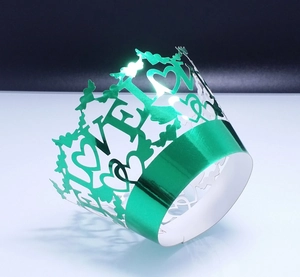 Macro detail of laser-cut green metallic cupcake wrapper with LOVE and heart patterns