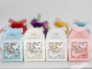 Close-up of laser-cut butterfly candy boxes with silk ribbons in multiple colors