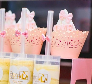 Pink laser-cut cupcake wrappers with heart motifs and sweet dessert push pop containers