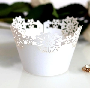 Macro shot of white laser-cut snowflake lace cupcake wrapper for festive dessert table