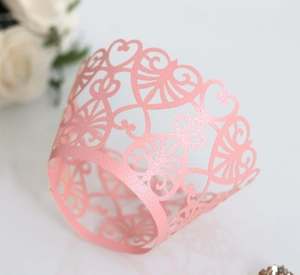 Close-up of pink laser-cut cupcake wrapper with elegant heart pattern for party decor