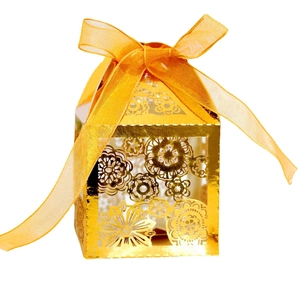 Macro shot of gold laser-cut hollow flower candy box with elegant orange ribbon bow