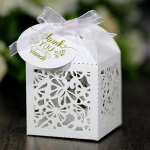 Laser-cut white wedding favor box with floral patterns and a thank you ribbon tag