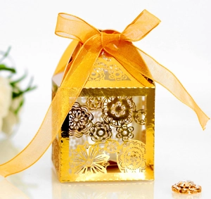 Detail of laser-cut floral pattern on golden wedding favor box with a satin ribbon