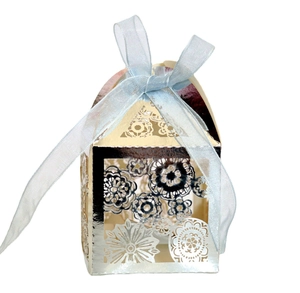 Detail of laser-cut floral pattern on silver gift box with a light blue organza ribbon