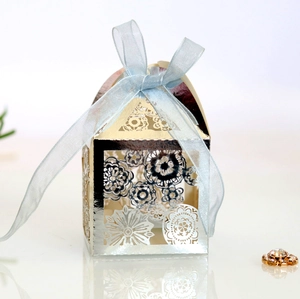 Macro shot of silver laser-cut floral favor box with a light blue translucent ribbon bow