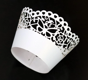 Detailed laser-cut cupcake wrappers with white butterfly and floral patterns on black background
