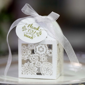 Elegant white laser-cut wedding favor box with lace pattern, ribbon, and thank you tag