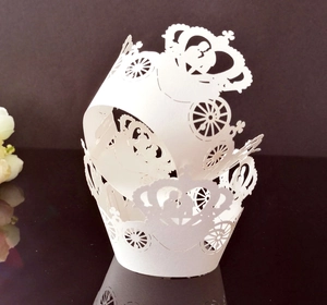Detailed laser-cut white cupcake wrapper featuring intricate pumpkin carriage designs