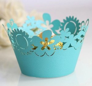Detailed laser-cut flower patterns on light blue paper cupcake wrappers for weddings