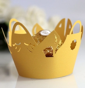 Macro detail of laser-cut gold crown cupcake wrapper with intricate hollow patterns