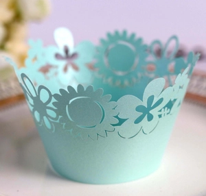 Detail of light blue laser-cut cupcake wrapper with intricate floral sunflower patterns