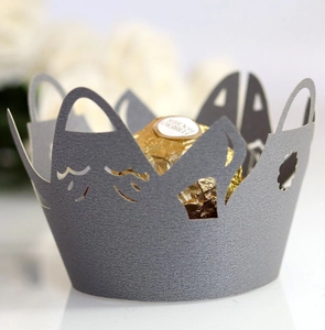 Macro detail of laser-cut crown cake wrapper with hollow patterns and a gold chocolate