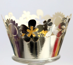 Macro view of laser-cut floral hollow cupcake wrapper with silver metallic finish