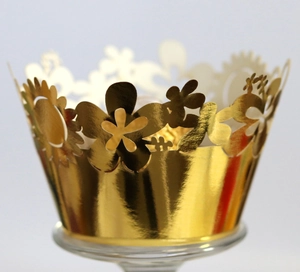 Close-up of laser-cut gold cupcake wrapper with intricate floral hollow design for weddings