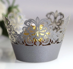 Close-up of silver laser-cut cupcake wrapper with elegant hollow crown pattern details