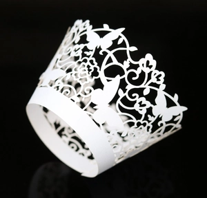 Macro detail of laser-cut white butterfly lace paper cupcake wrappers for weddings