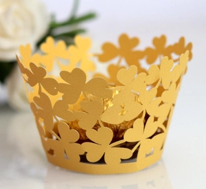 Detail of laser-cut gold clover pattern on cupcake wrappers with elegant hollow design