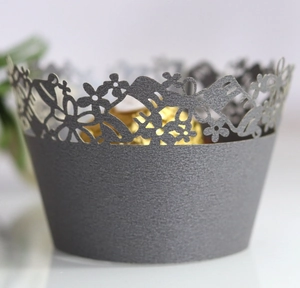 Macro view of dark grey laser-cut cupcake wrapper with floral and butterfly patterns