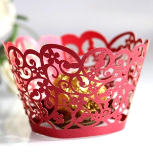Intricate red hollow laser-cut cupcake wrappers with floral patterns for wedding decor