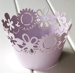 Close-up of laser-cut lavender cupcake wrappers with intricate floral daisy pattern