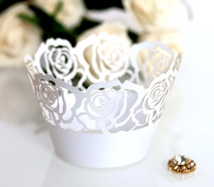 Detailed laser-cut white rose pattern on decorative cupcake wrappers for weddings