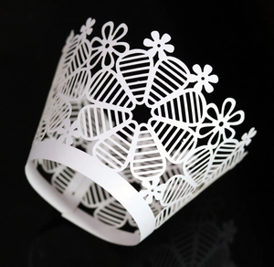 Intricate laser-cut white cupcake wrapper with floral pattern for elegant party decor