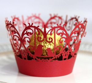 Detail of red laser-cut cupcake wrapper with bird and floral scroll patterns