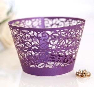 Detailed laser-cut vine patterns on purple cupcake wrappers for dessert table decoration
