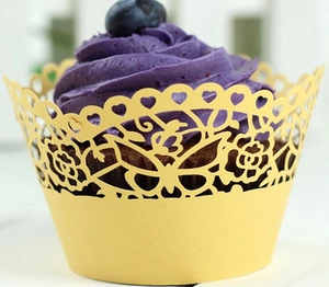 Detail of yellow laser-cut cupcake wrapper with butterfly and rose lace patterns