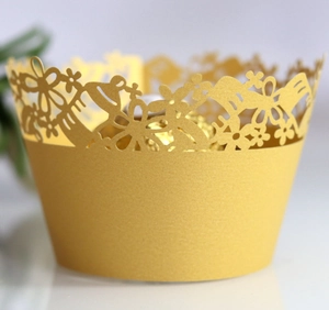 Macro detail of laser-cut pearlescent gold cupcake wrapper with intricate floral hollow design