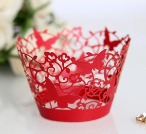 Close-up of red laser-cut cupcake wrapper with intricate butterfly and floral patterns