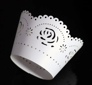 Macro view of white pearlescent paper cupcake wrappers with laser-cut rose patterns