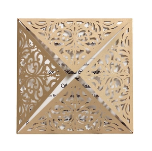 Close-up of laser-cut champagne gold square wedding invitation with elegant scroll pattern