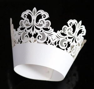 Close-up of laser-cut ivory white cupcake wrapper with intricate lace crown patterns