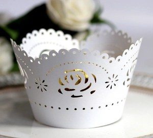 Intricate laser-cut white rose cupcake wrapper with decorative scalloped edges and star patterns